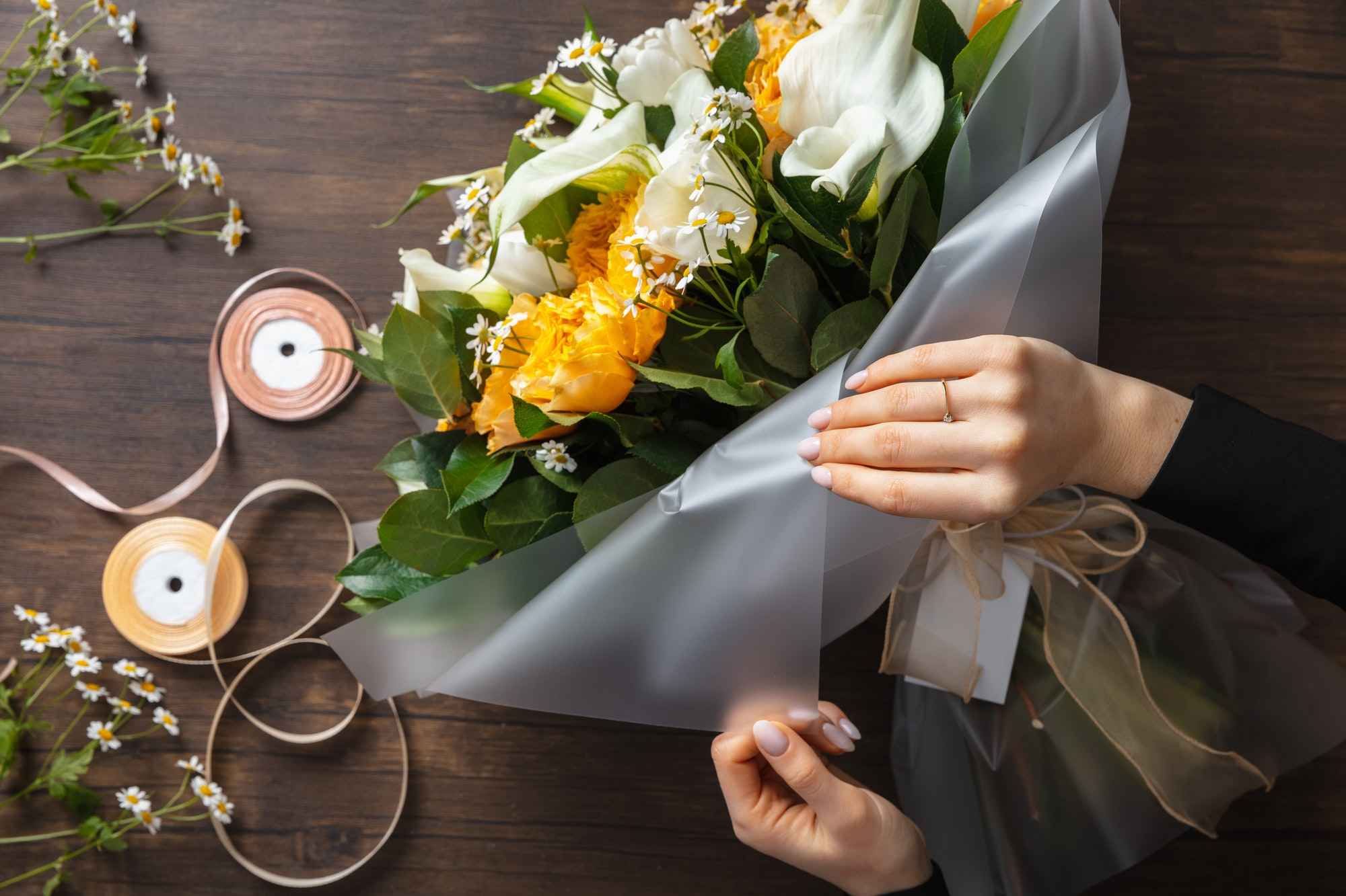 Florist at work: woman making fashion modern bouquet of different flowers on wooden background